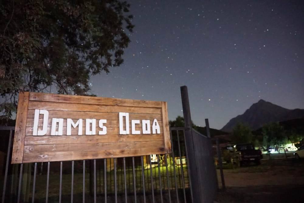 Letrero de ingreso a Domos Ocoa de noche, bajo un cielo estrellado