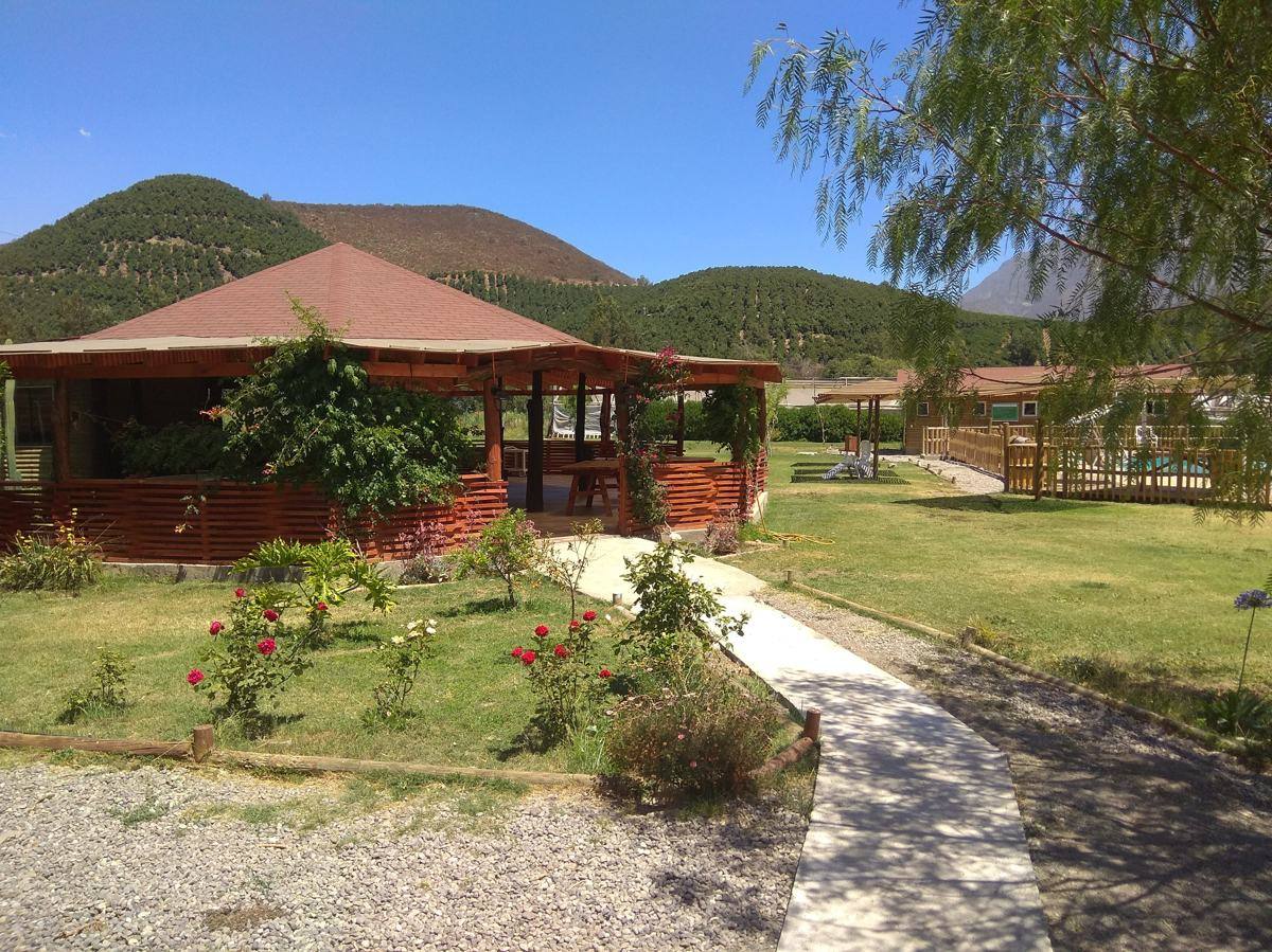 Covered BBQ house with gardens and pool in the background
